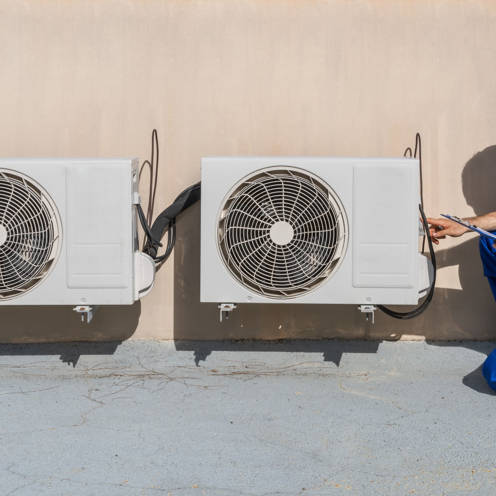 A man working on outdoor air conditioning units.