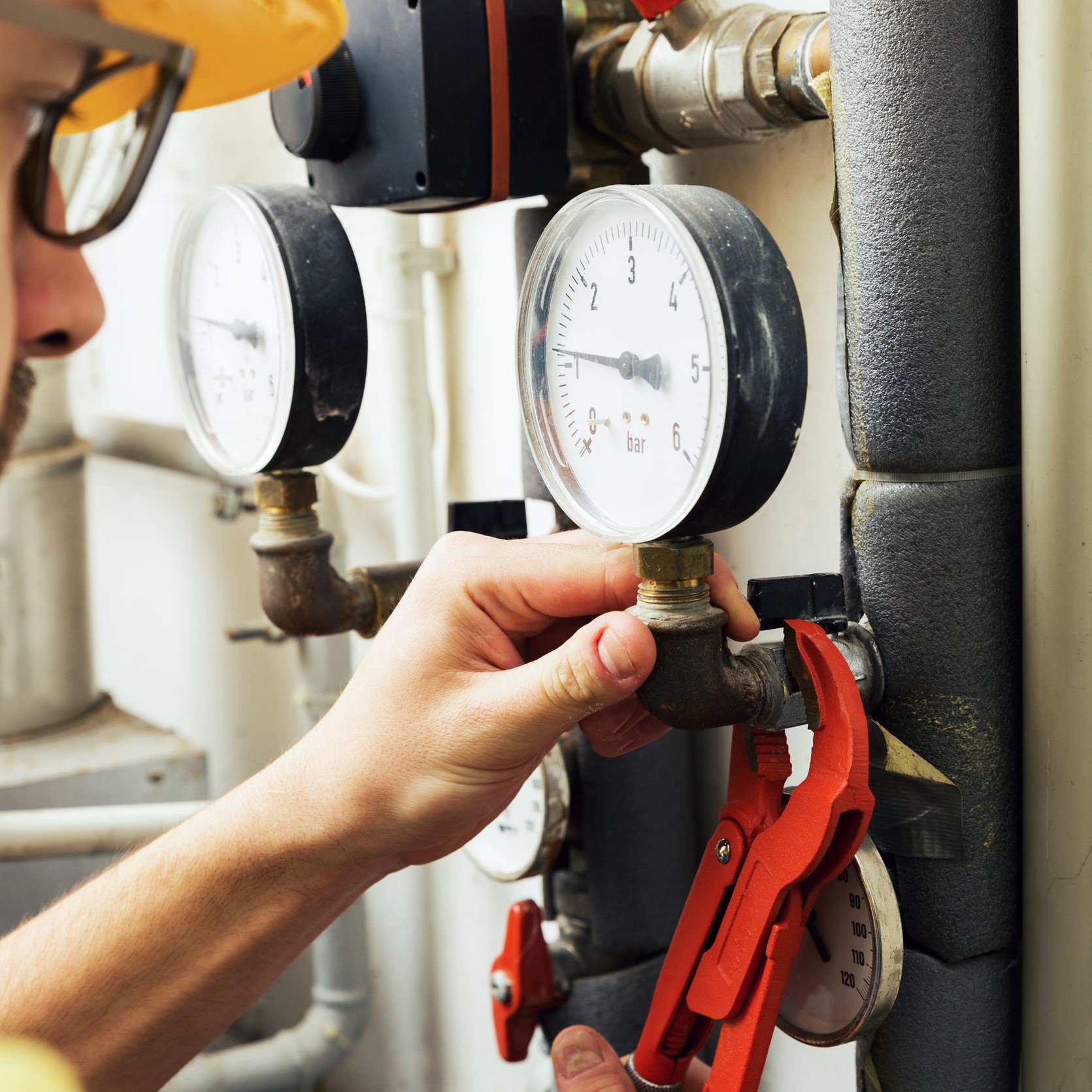 A repairman checking and adjusting the gas pressure of a furnace. 