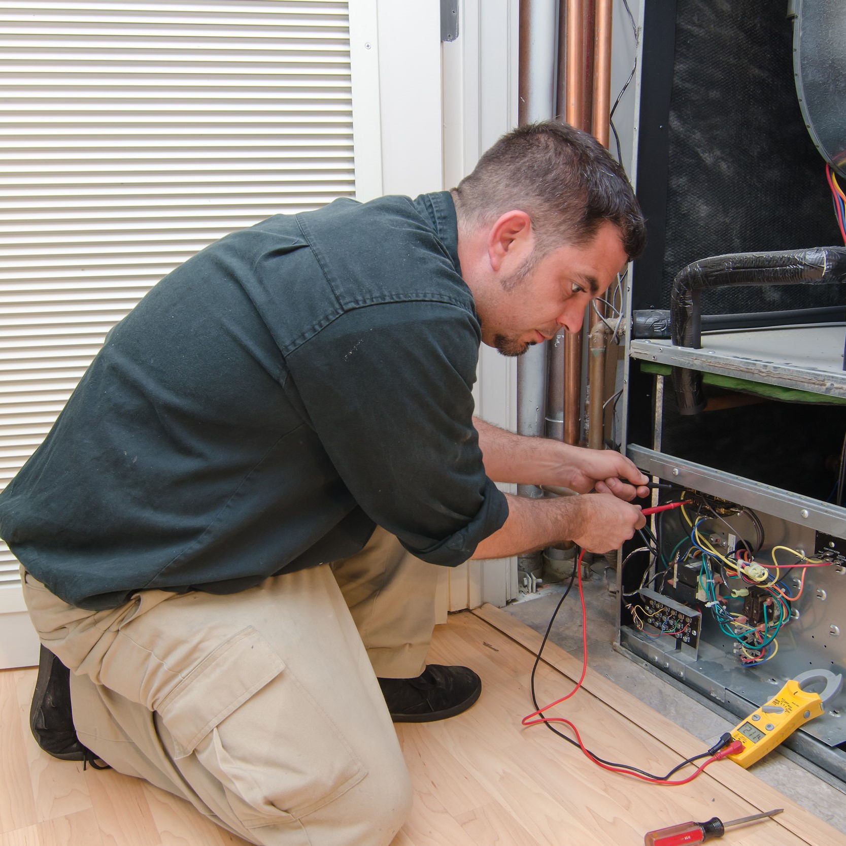 A technician checking out the pressure switches inside a furnace, as well as other parts.