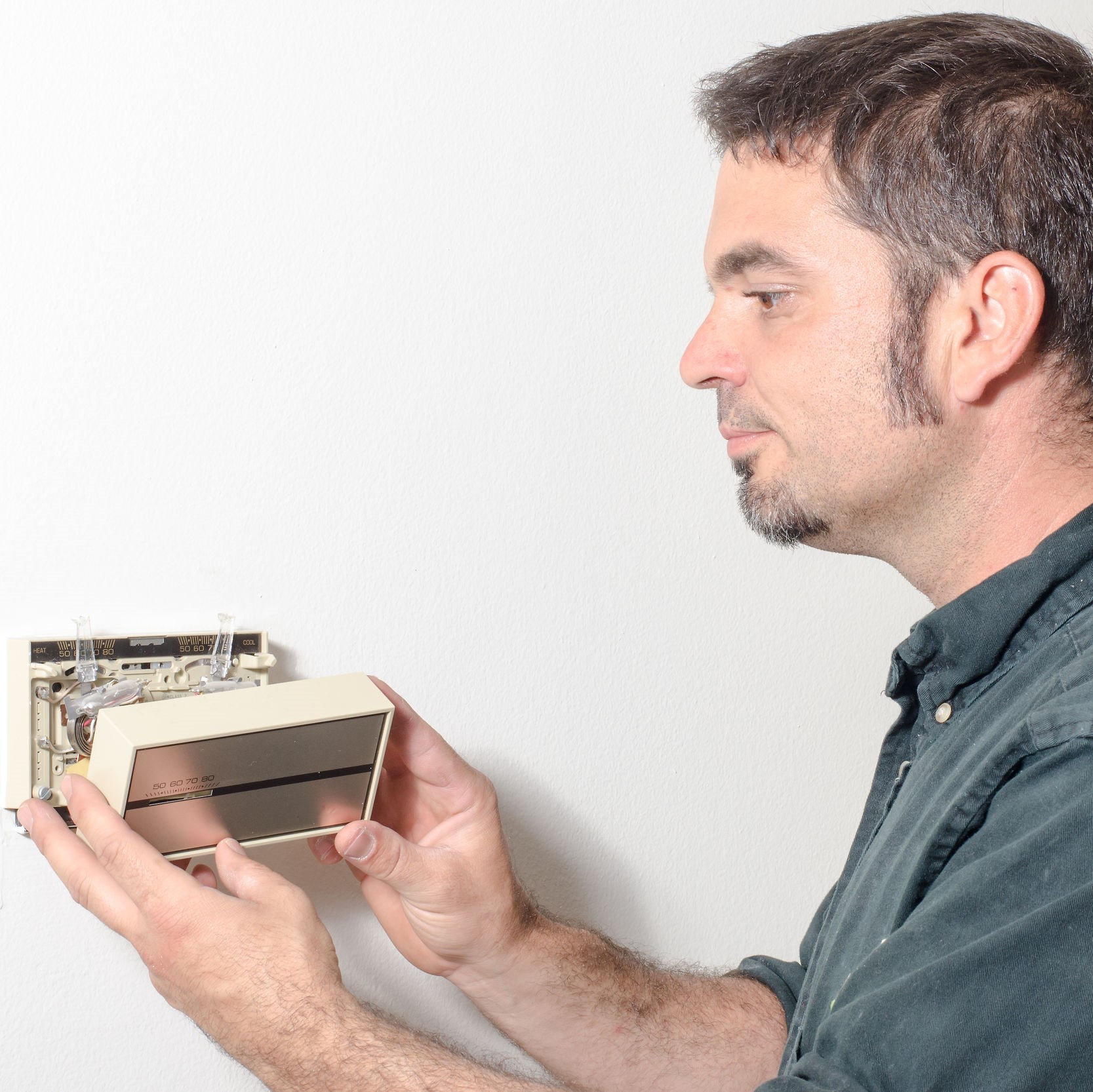 A technician replacing a thermostat on the wall.