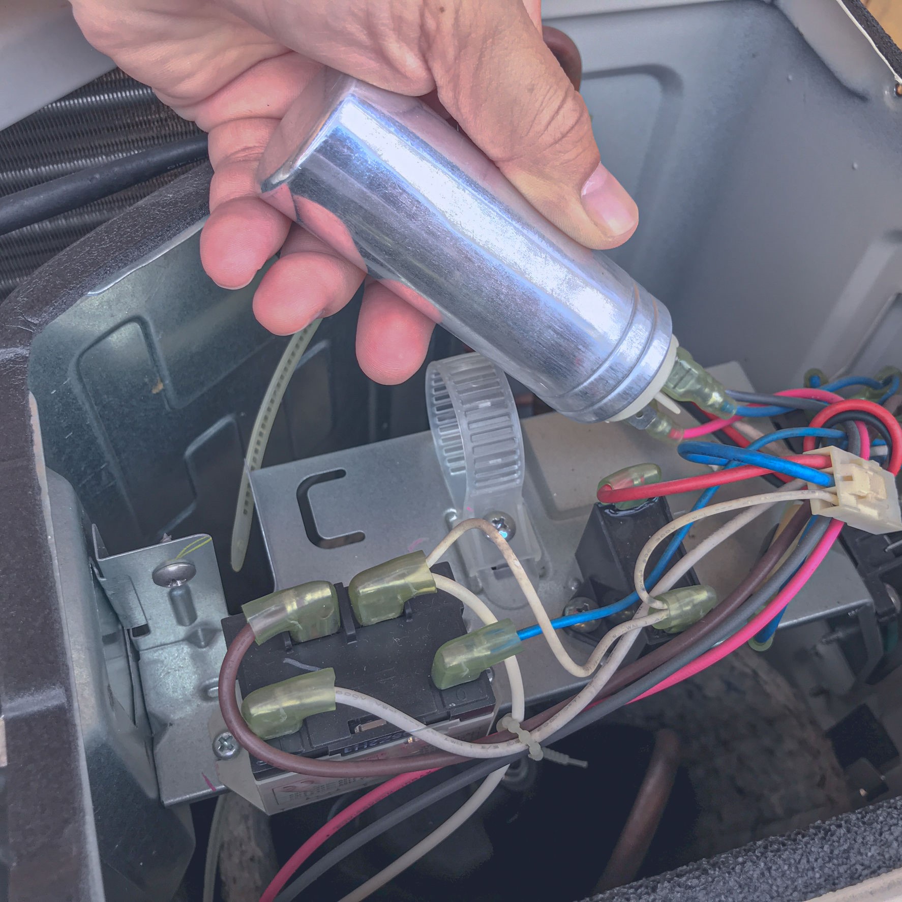 A worker replacing a capacitor in a heater.