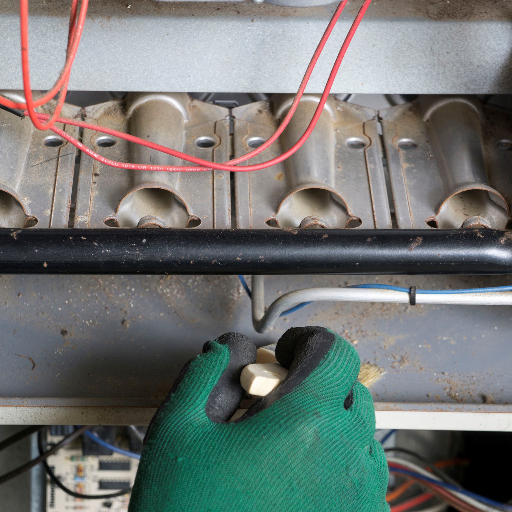 A worker looking at a heater that needs to be repaired.