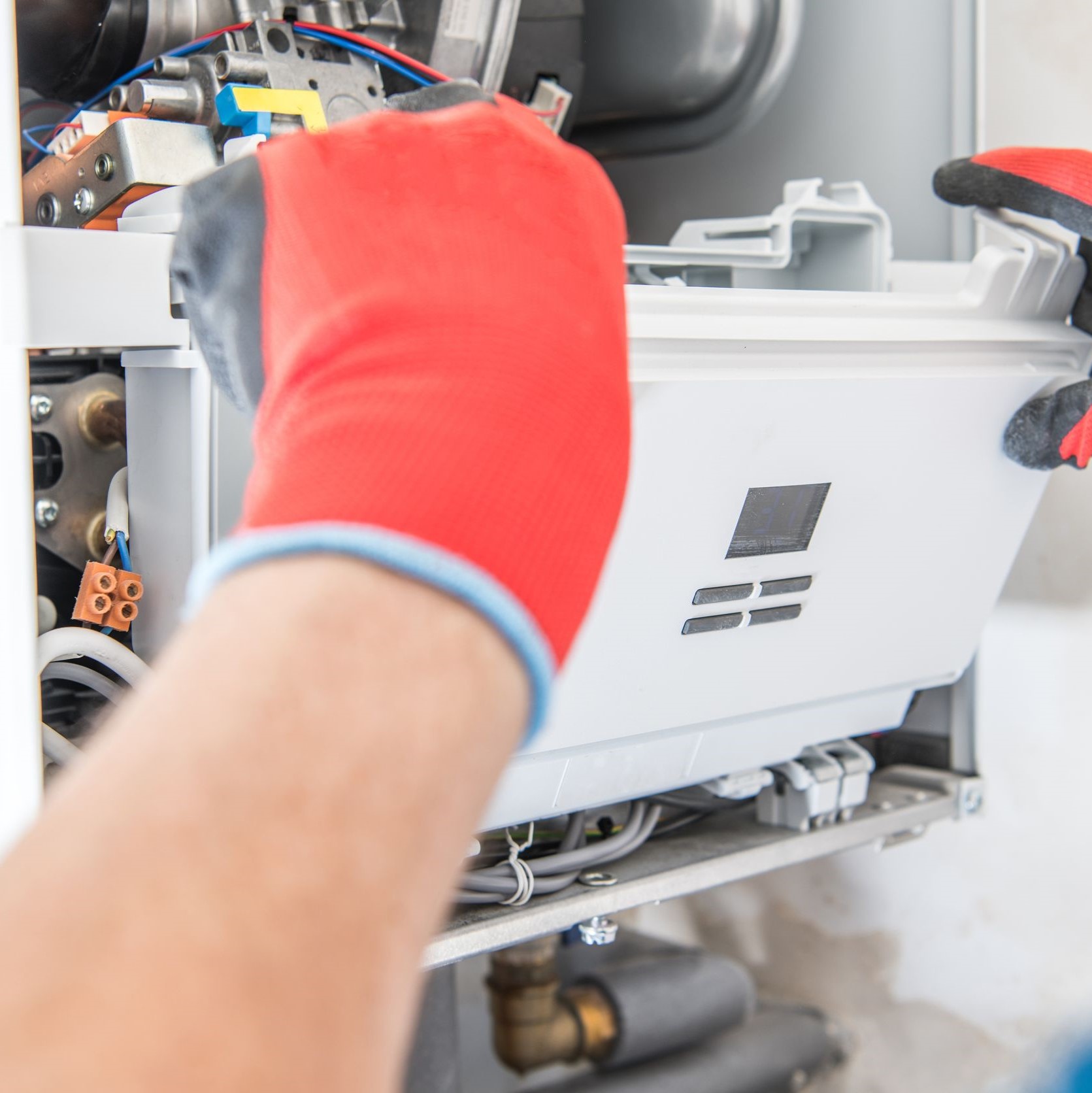 Gloved hands working on a furnace. 